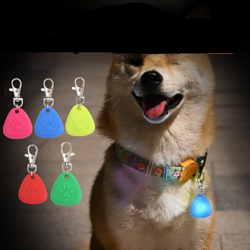 A silicone triangle pendant light in various colors shown with a dog wearing one of the pendants attached to a collar.
