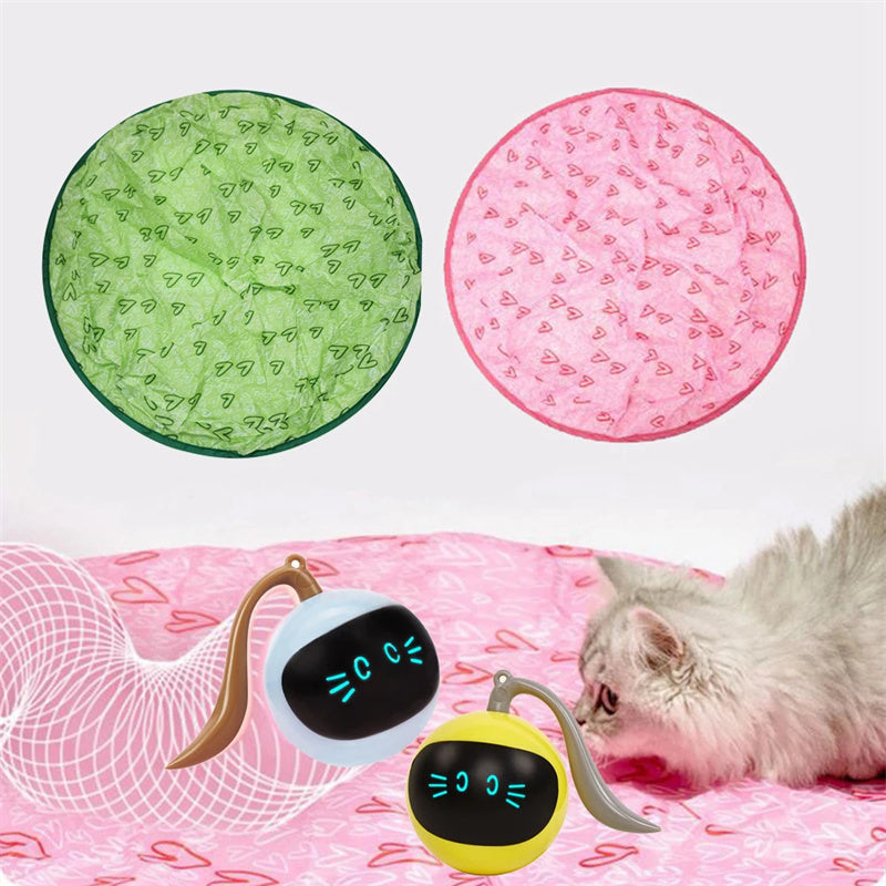The image shows a cat interacting with a pink hunting cover and a green hunting cover, along with a USB-powered electric toy ball.