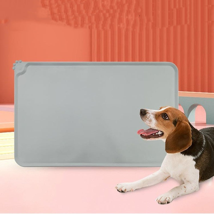 A silicone pet placemat shown in a gray color with a dog sitting in front of it.