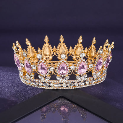 Gold and pink gemstone tiara on a reflective surface with a dark background