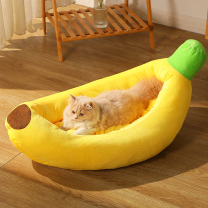 Cat lying on a banana-shaped pet bed in a room with wooden flooring.