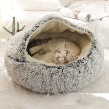 A cat resting inside a gray, hooded, plush pet bed.