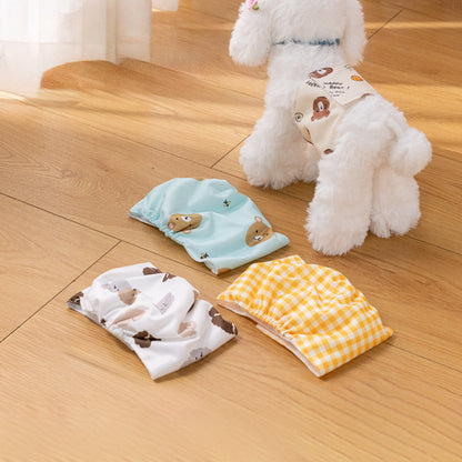 Reusable pet sanitary pants for dogs, displayed in three variations - blue with white dots, white with a yellow checkered pattern, and a white base with a yellow paw print design. A white dog with a similar yellow paw print design is also present in the background.