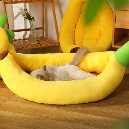 Cat lying on a yellow banana-shaped pet bed with green tips in a home setting.
