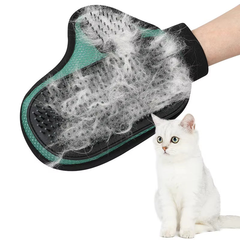 A hand wearing a black and green pet grooming glove with silicone tips, holding a clump of cat hair, next to a white cat.