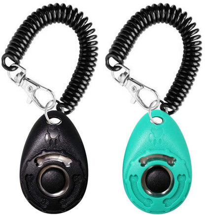 A selection of pet training clickers in various colors with a key ring, attached to a spring cord, and being used by a person training a dog.