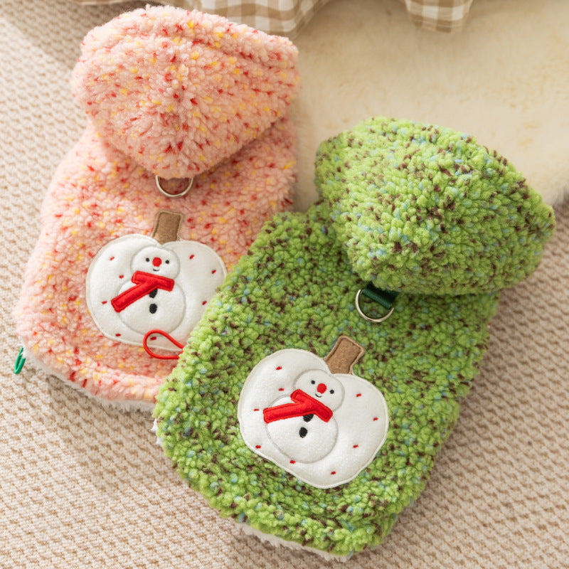 Two textured slippers, one pink and one green, with snowman decorations on a beige fabric background.